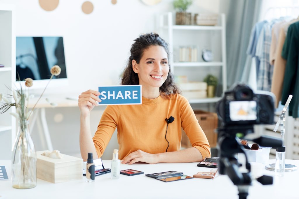 Beauty Blogger Holding Share Sign